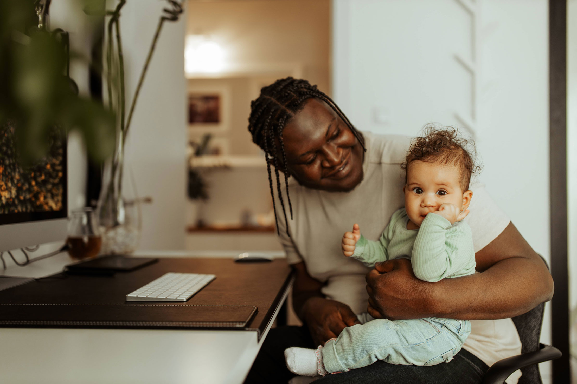 Mann am Schreibtisch mit Baby auf dem Schoß