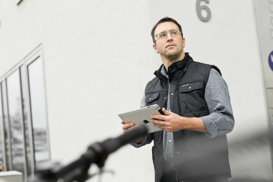 Mitarbeiter eines Wohnungsunternehmens arbeitet mobil mit einem Tablet.