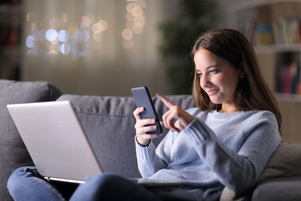 Junge Frau sitzt mit Handy auf der Couch Junge Frau sitzt mit Handy auf der Couch