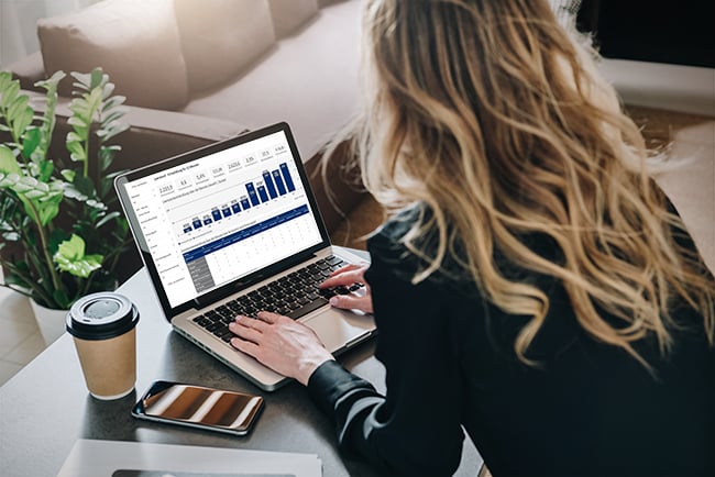 Frau arbeitet an ihrem Laptop und hat Kaffee neben sich stehen