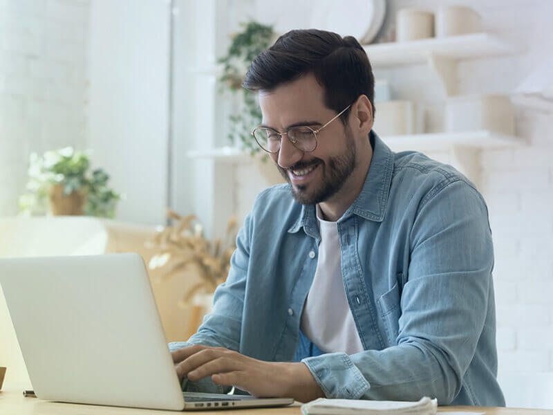Mann lächelt hinter seinem Laptop